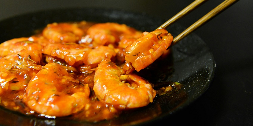 A picture of a plate of garlic shrimp served with herbs and garnished with lemon slices.