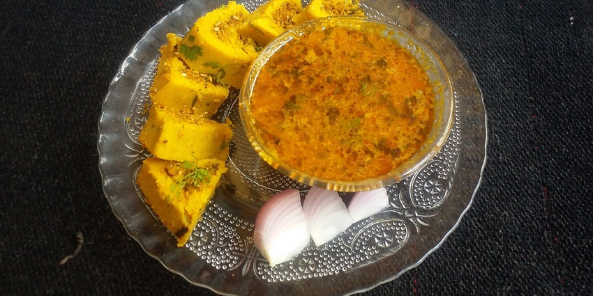 Indian dish with spicy curry, rolled flatbread, and sliced onions, dining options near Lenyadri Caves.