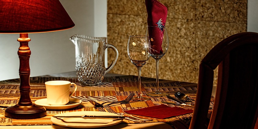 An elegant dinner table is set at a restaurant with plates, cutlery, and glasses in soft lighting.