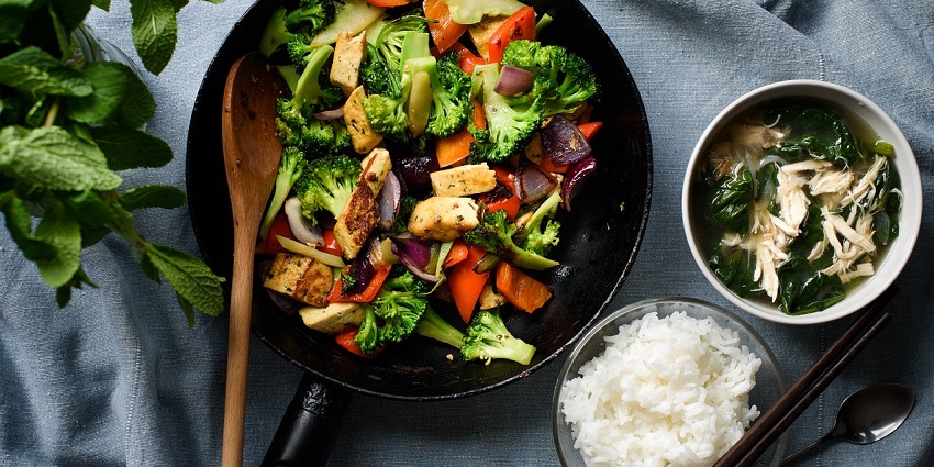 Tofu dish with colourful vegetables garnished with herbs on a white plate.