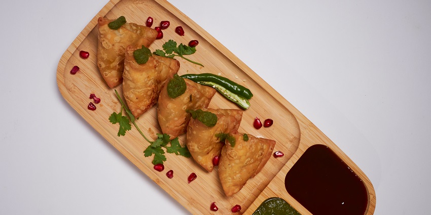 Samosas, green and red chutney garnished with pomegranate and coriander leaves
