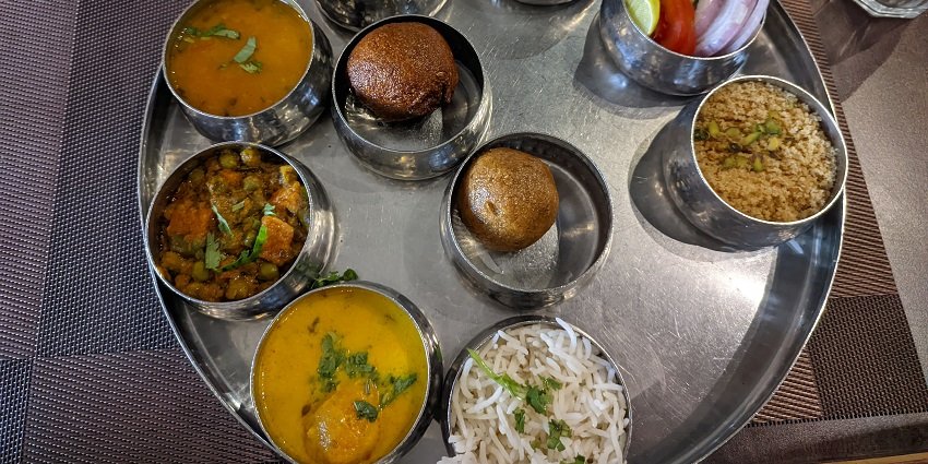 A Traditional Rajasthani Thali with Dal Baati, Churma, Pulav, and three different kinds of curry