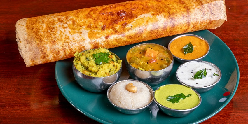A mouth-watering view of a plate served with South Indian food kept on a flat surface.