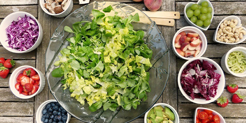 A bowl of fresh fruit salad with berries, kiwi, and orange slices on a table.