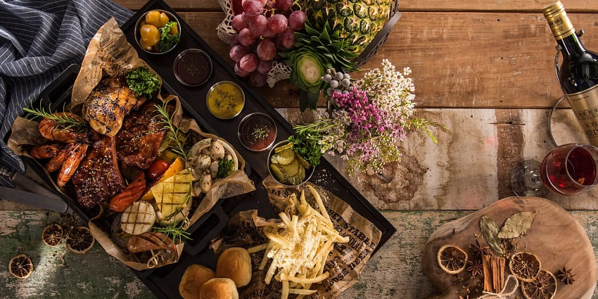 A platter of assorted starters with dips, vegetables, and snacks on a wooden table