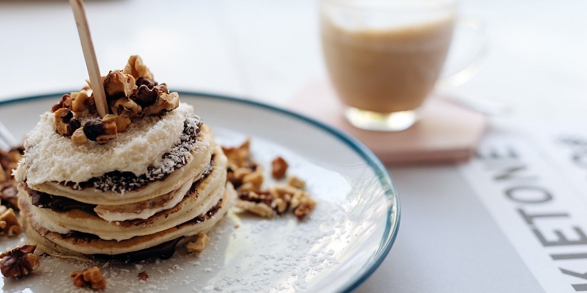 A stack of fluffy pancakes topped with syrup and fresh fruit is served for breakfast
