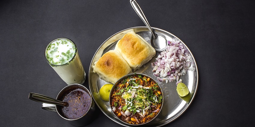A plate of misal pav served with red chutney and lassi at a local eatery nearby