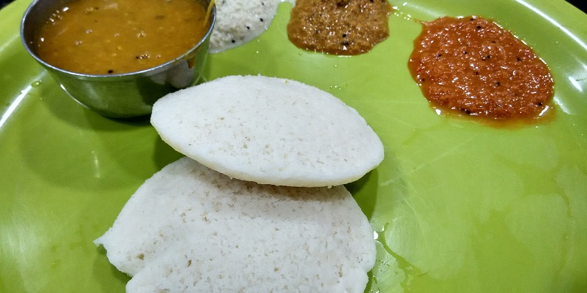A plate of steamed white idlis served with green chutney in Tamil Nadu