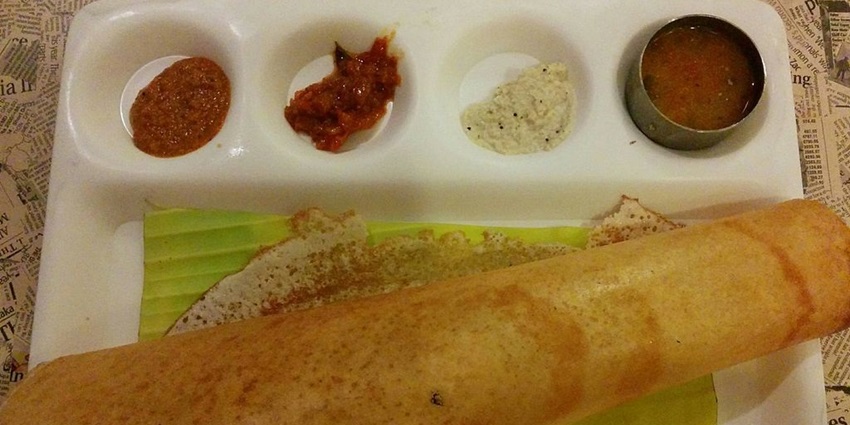 Delicious dosa served with chutneys and sambar on a banana leaf plate