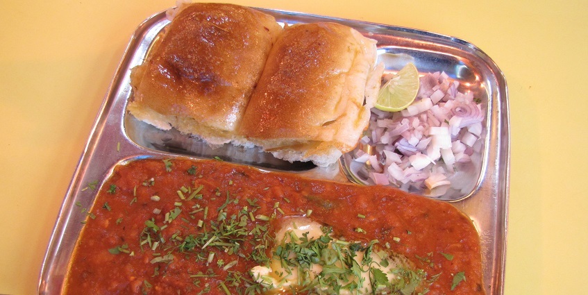 Image of pav bhaji served on a steel plate in a restaurant - delicious looking