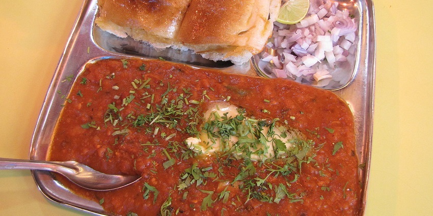A plate of pav bhaji served with onions and lemon, available at a local eatery nearby