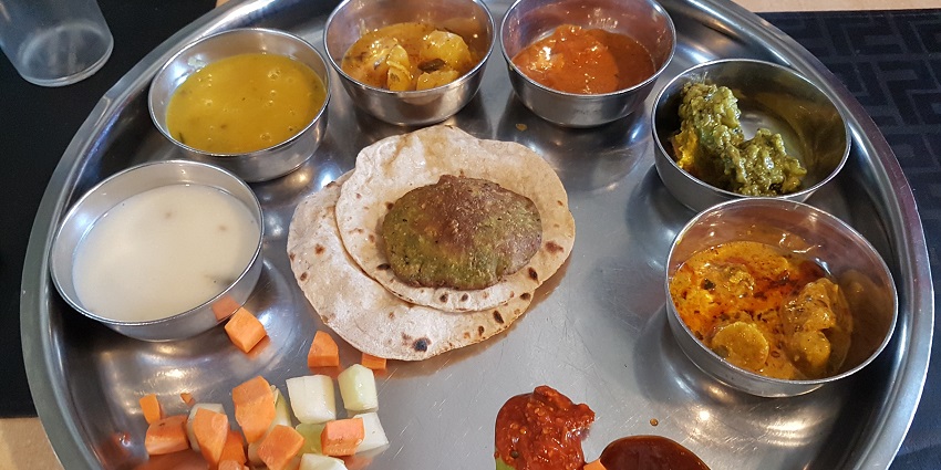 A delicious view of a Gujarati Thali with a variety of cooked vegetables and flatbreads.