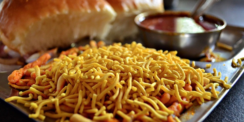 A plate of Maharashtra's Misal Pav, a popular Indian dish, featuring a bowl of spicy curry.