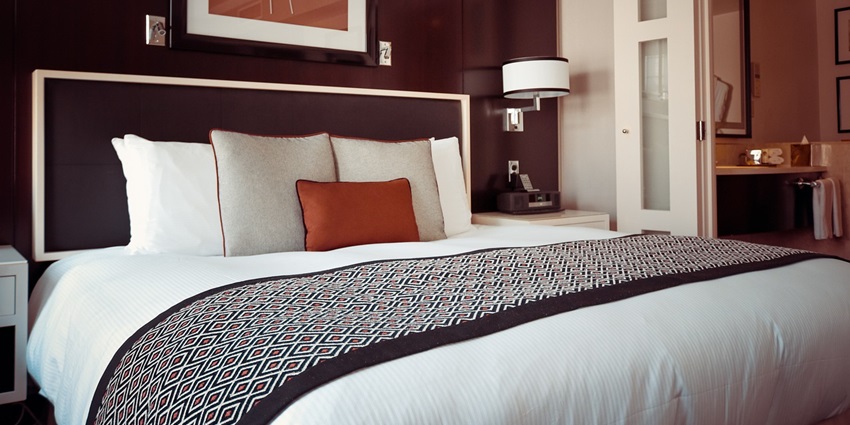 A view of a hotel room featuring a neatly made bed with fluffy pillows and soft linens.
