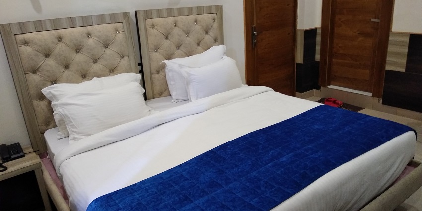 Image of a hotel room with a bed, clean sheets and pillows perfect for your travel