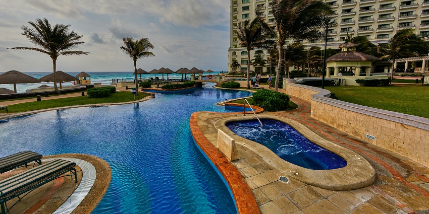 A marvellous view of a hotel with stunning architecture in front of a swimming pool.