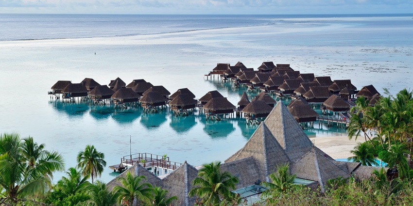 Image of overwater bungalows surrounded by clear blue waters in a beach