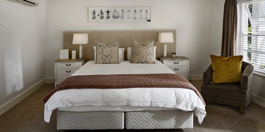 A view of a modern bedroom with a large bed in the centre of the room with serene vibe.