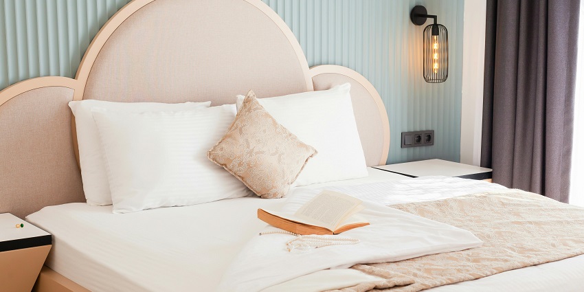Stylish hotel bed with fluffy pillows and a captivating book for a perfect stay!