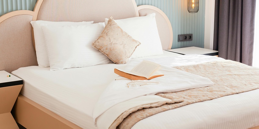 Stylish hotel bed with fluffy pillows and a captivating book for a perfect stay!