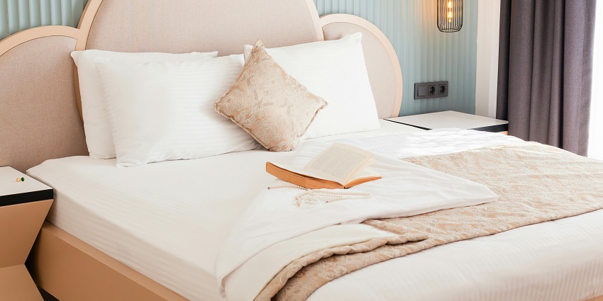 Cozy hotel bed adorned with plush pillows and an inviting book for relaxation
