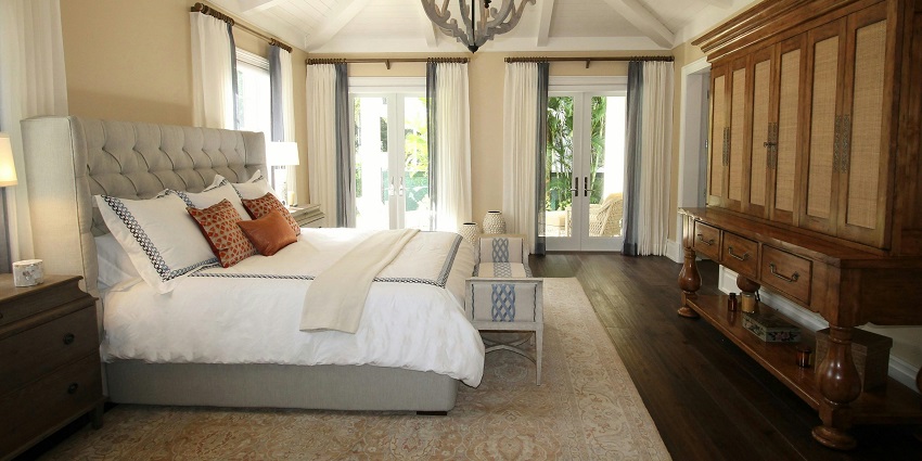 An image of a hotel room with a cozy and upholstered bed