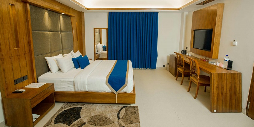 A hotel room interior featuring a bed and large windows showcasing modern design.