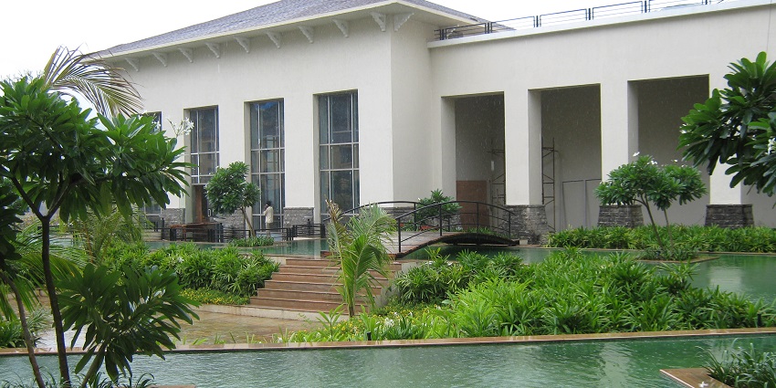 Image of a hotel courtyard is surrounded by greenery during day time