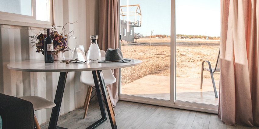 A luxurious hotel bedroom with a panoramic view of the outside and modern decor.