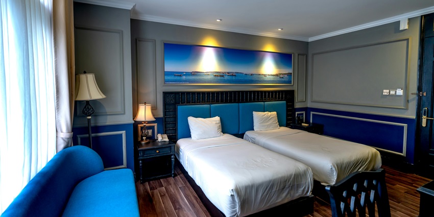 Hotel room featuring blue furniture and white bed linen, located in a stylish setting.