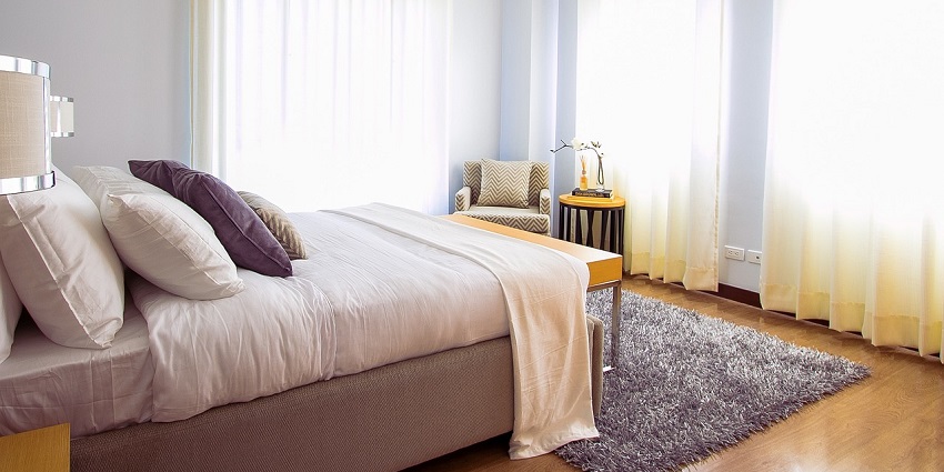 A cosy bedroom with a plush carpet beneath a stylish bed, creating a warm atmosphere