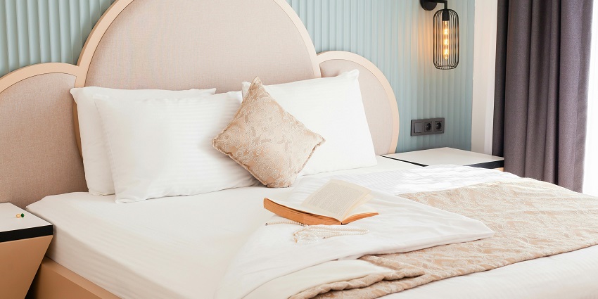 Relax in a comfy hotel bed with soft pillows and an inviting book for a peaceful retreat.