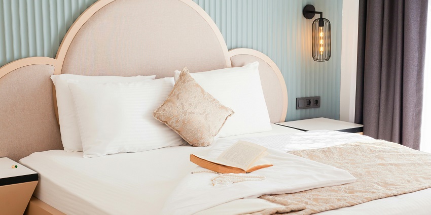 Relax in a comfy hotel bed with soft pillows and an inviting book for a peaceful retreat.