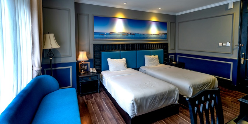 A hotel room featuring blue furniture and white bed linen at a modern hotel.