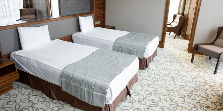 A neatly arranged and well-lit hotel room, featuring a bed, chair, and sofa