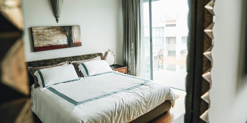 Cosy, well-lit bedroom with a large bed, white linens, and a modern wooden design