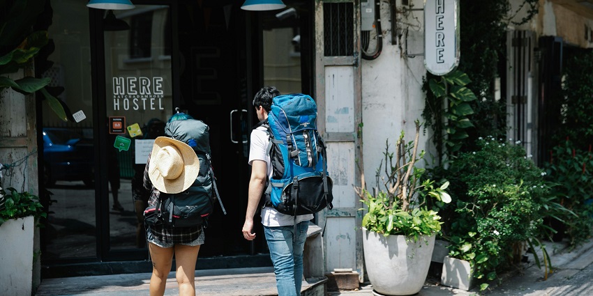 A couple of travellers with backpacks walk into a hotel entrance, ready for their stay.
