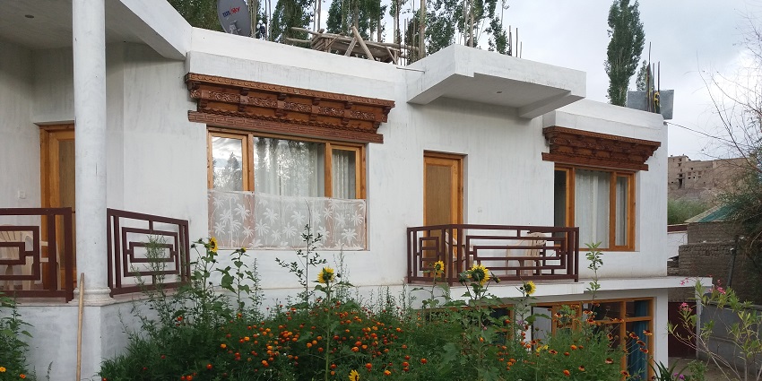 A picture of a guest house in Ladakh with a garden having flowers