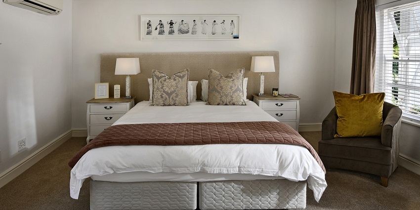 A fantastic view of a hotel room with a grey bed lined with white sheets and pillows.
