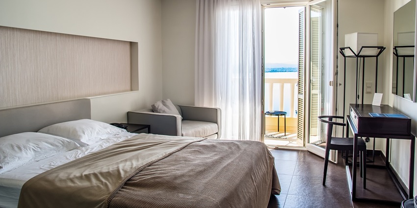 Room with a bed, balcony overlooking a lake, and stylish decor offering comfortable stays.