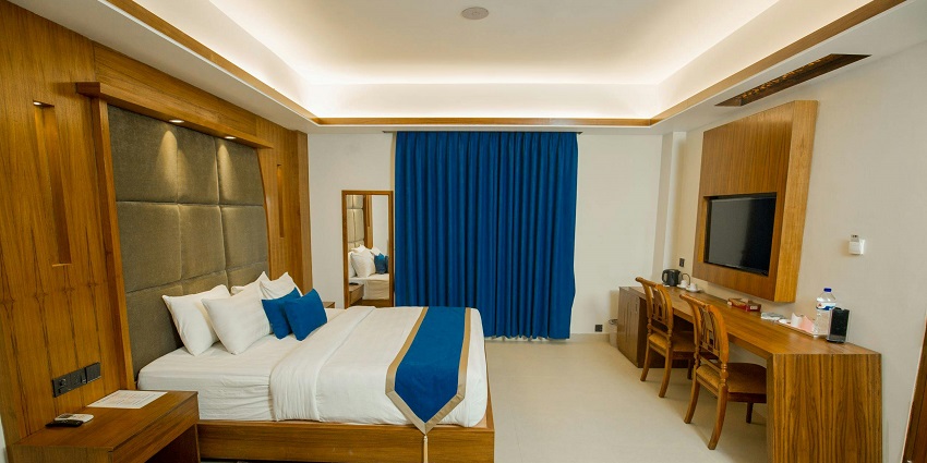 Interior view of a hotel room featuring a bed, desk, and large windows in a modern design.