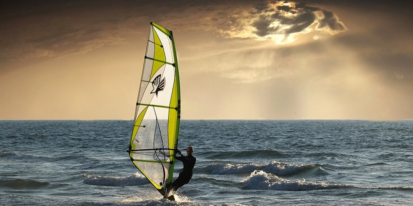A picture of a Windsurfer balancing and riding, one of the best Alibaug Beach water sports.
