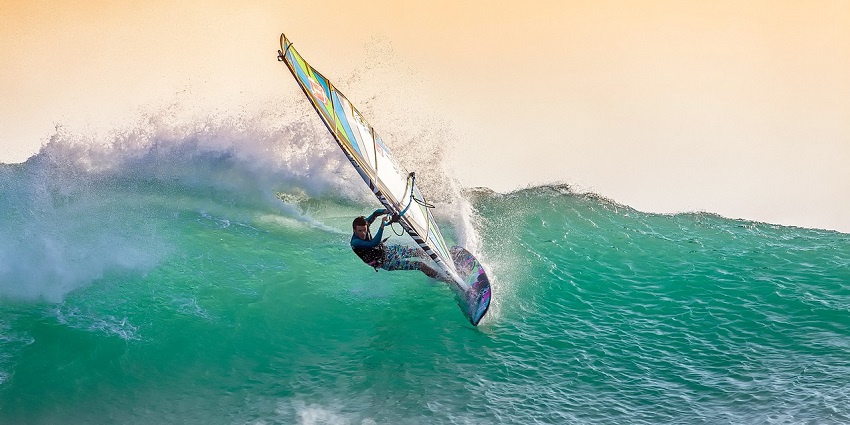 A windsurfer riding the breeze and waves at Panshet Lake, surrounded by hills.