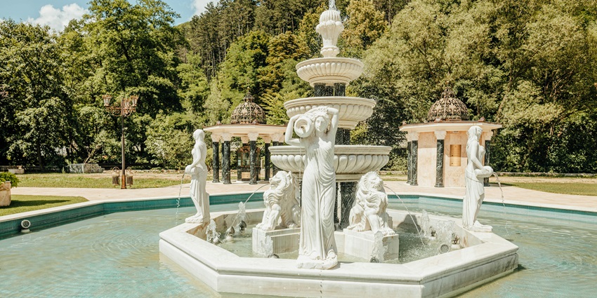 The beauty of an outdoor fountain surrounded by green trees, reminiscent of Anand Mahal.