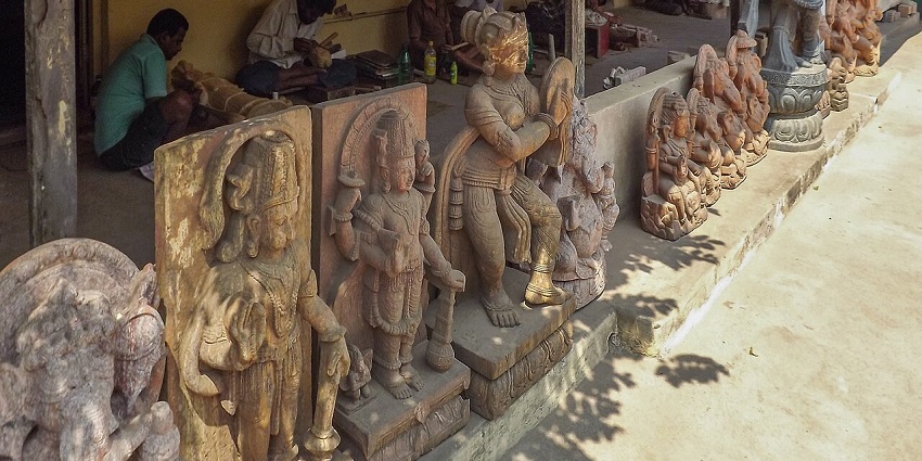 Busy artisans sitting behind rows of beautiful idols and working on their crafts.
