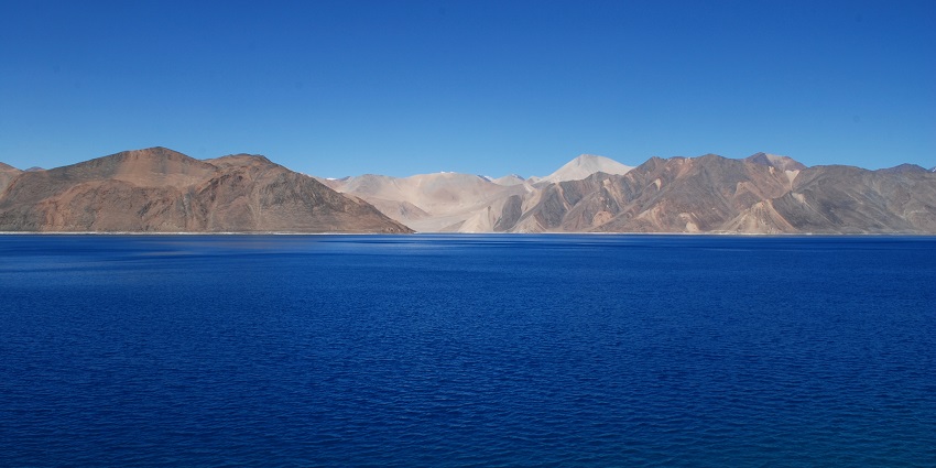 Image of clear blue water lake and surrounded by mountain under blue sky