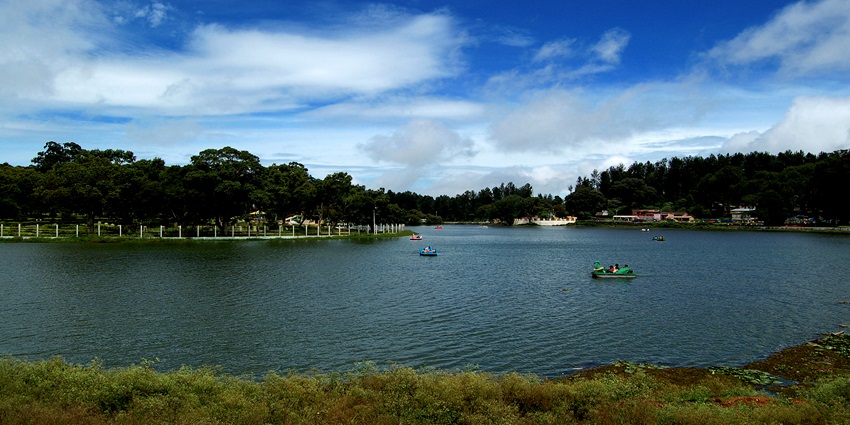 A picture of a lake with a boat sailing in the middle