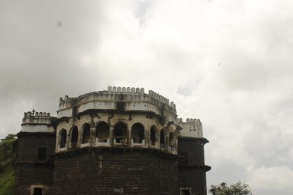 Majestic view of Ambagad Fort atop a hill surrounded by lush greenery.