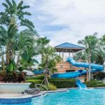 Group of people enjoying a sunny day by the swimming pool, surrounded by palm trees