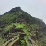 Majestic view of Asherigad Fort atop a hill surrounded by lush greenery